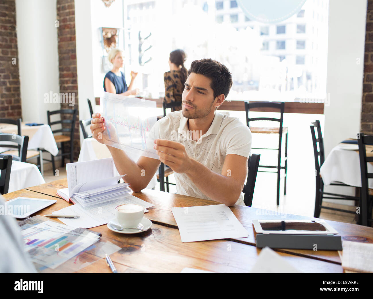 Businessman examining documents dans cafe Banque D'Images