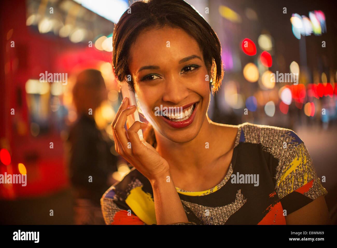 Woman taking on cell phone on city street at night Banque D'Images