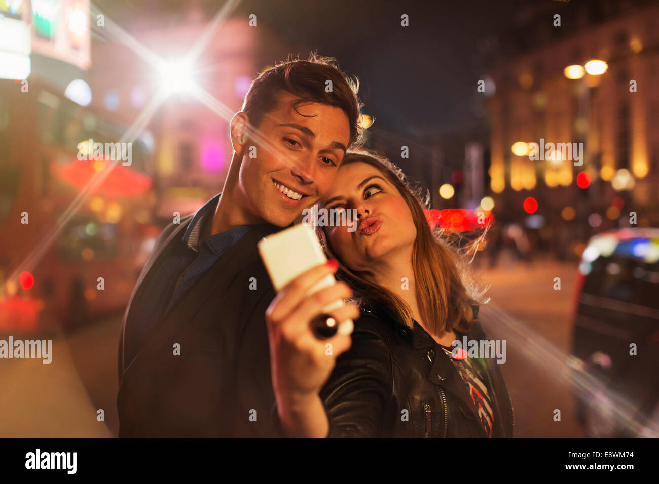 Couple taking photo avec téléphone cellulaire pendant la nuit Banque D'Images