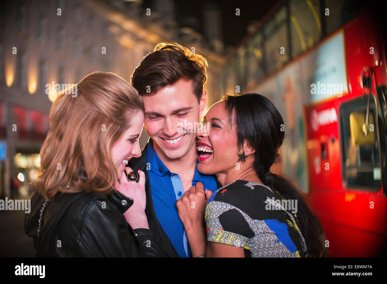 Friends hugging on city street at night Banque D'Images