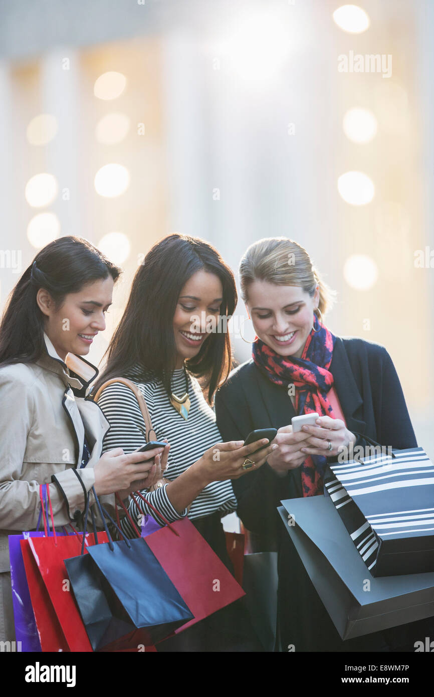 Les femmes utilisant des téléphones portables on city street Banque D'Images