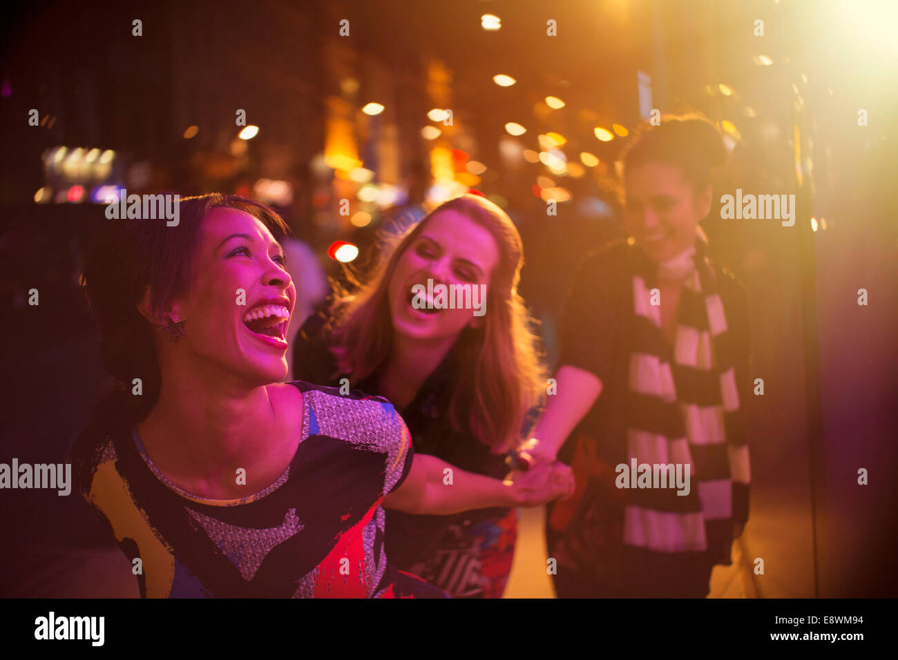 Les femmes rient ensemble on city street at night Banque D'Images