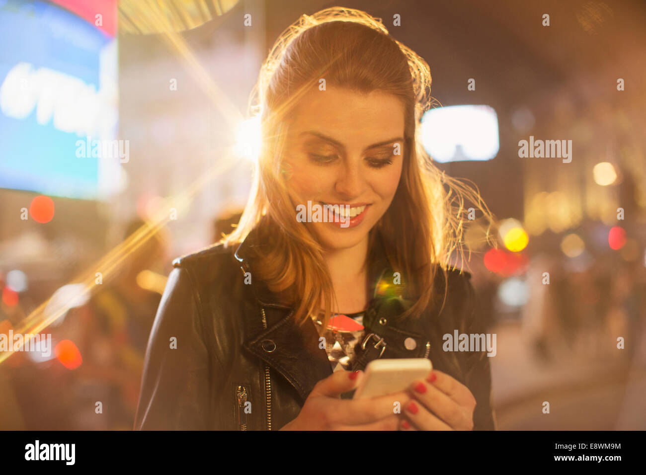 Woman using cell phone on city street at night Banque D'Images