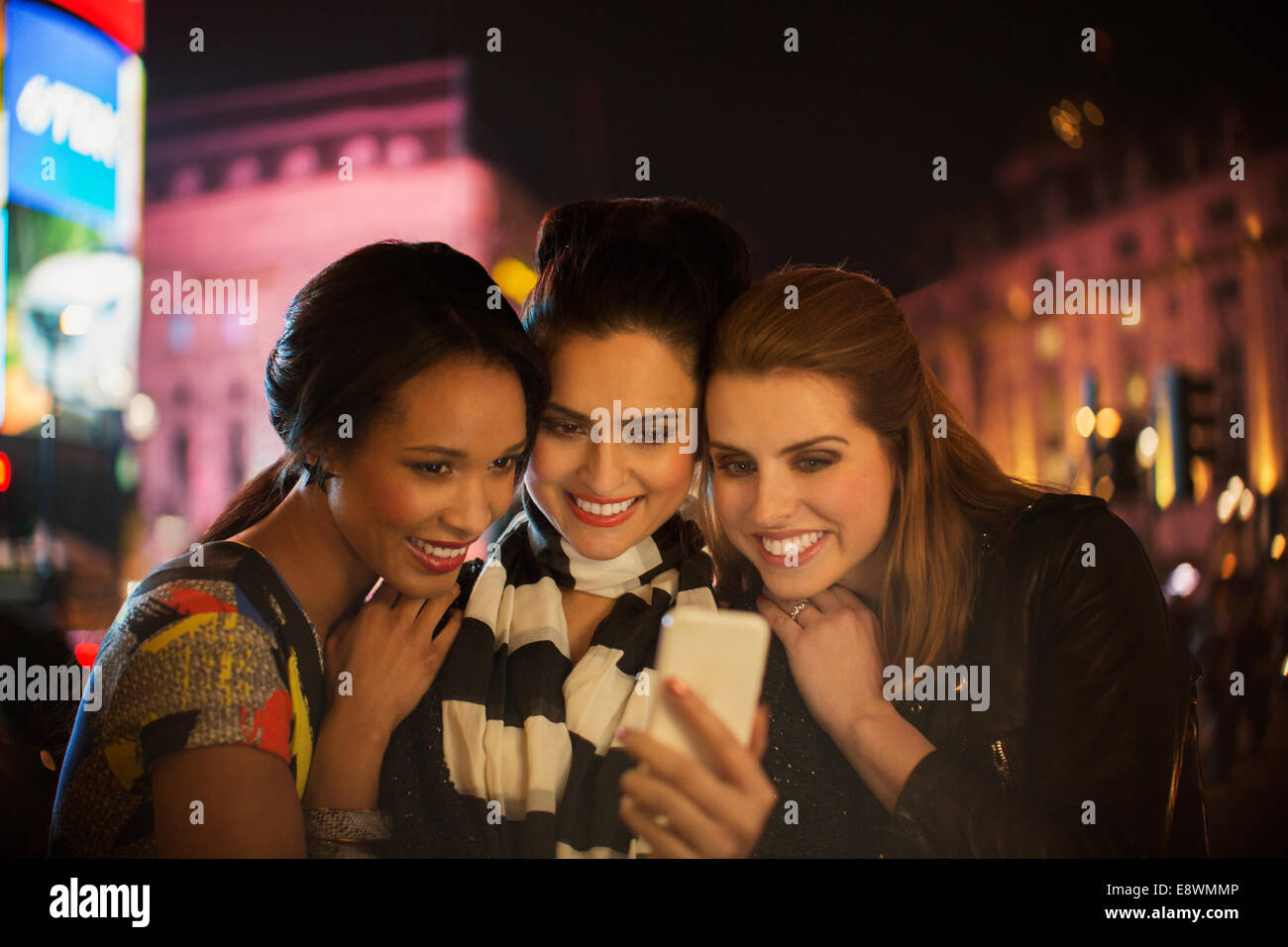 Des femmes qui parlent photo ensemble on city street at night Banque D'Images