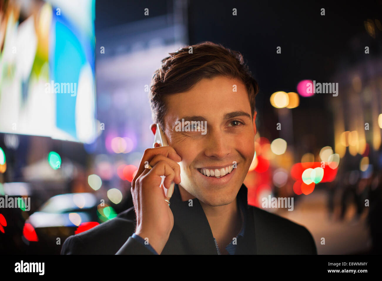 Man talking on cell phone on city street at night Banque D'Images
