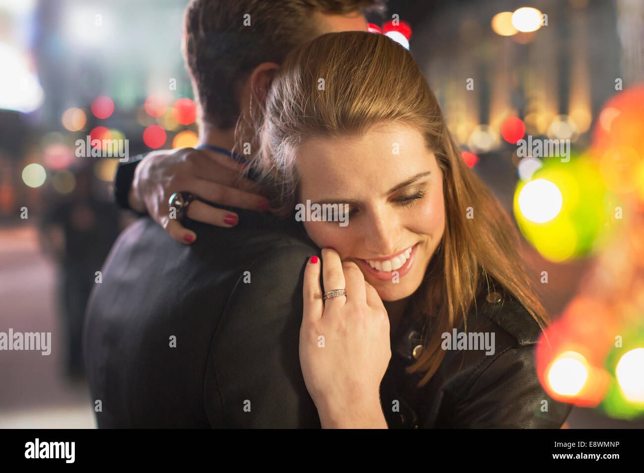 Couple hugging on city street at night Banque D'Images