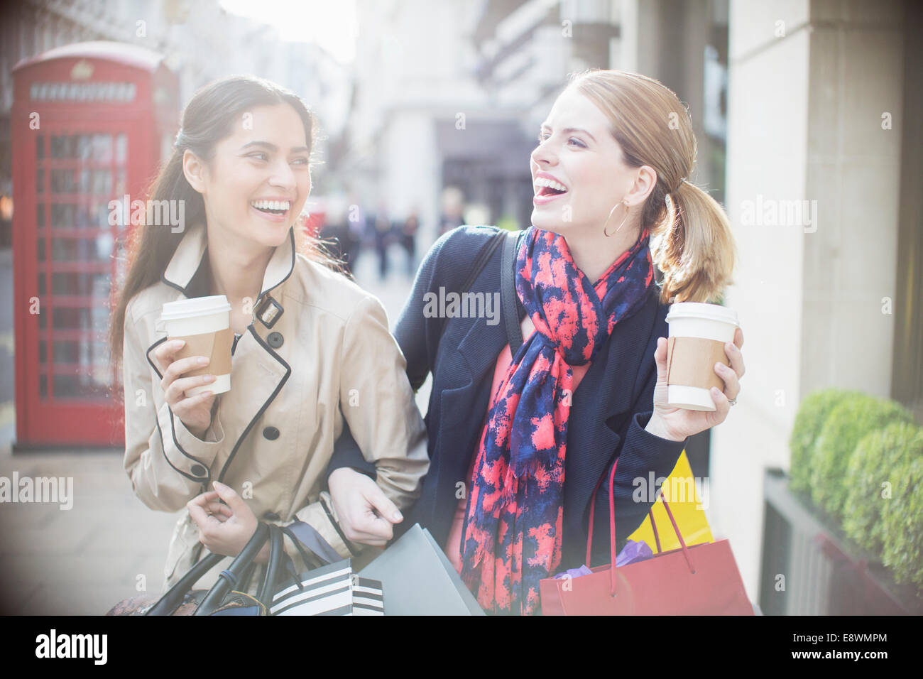 Les femmes de boire du café ensemble on city street Banque D'Images