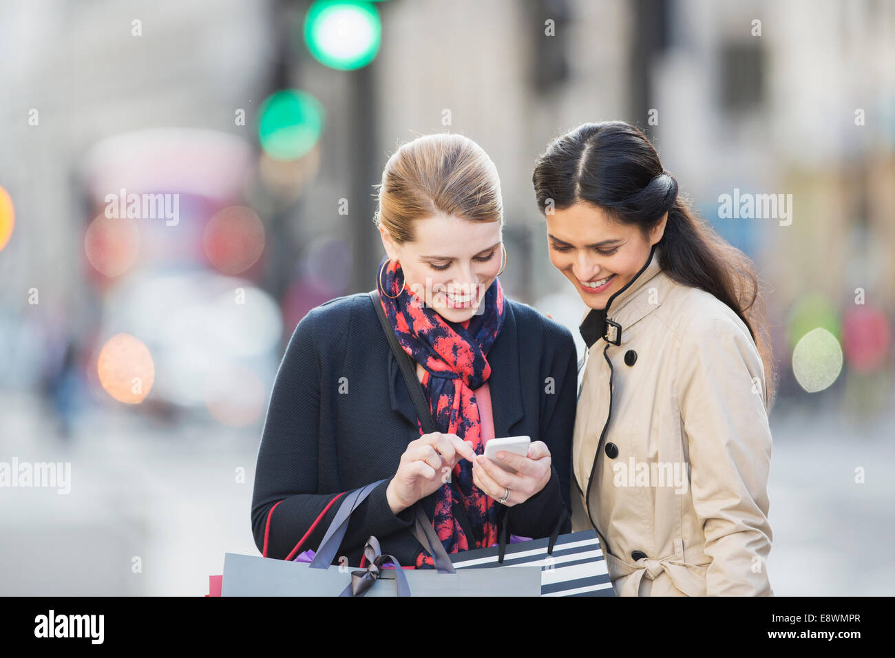 Les femmes à la recherche de cell phone on city street Banque D'Images