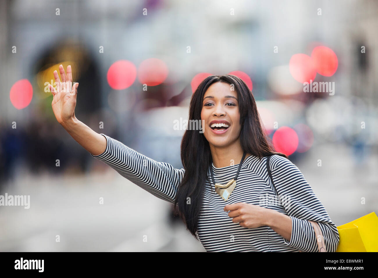 Woman waving pour taxi on city street Banque D'Images