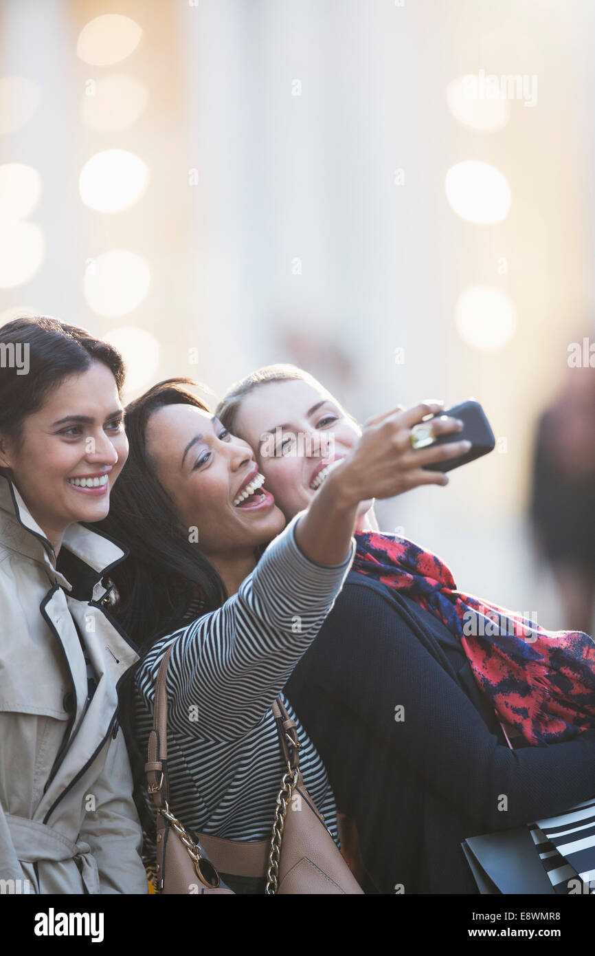 Amis parler photo avec cell phone together on city street Banque D'Images