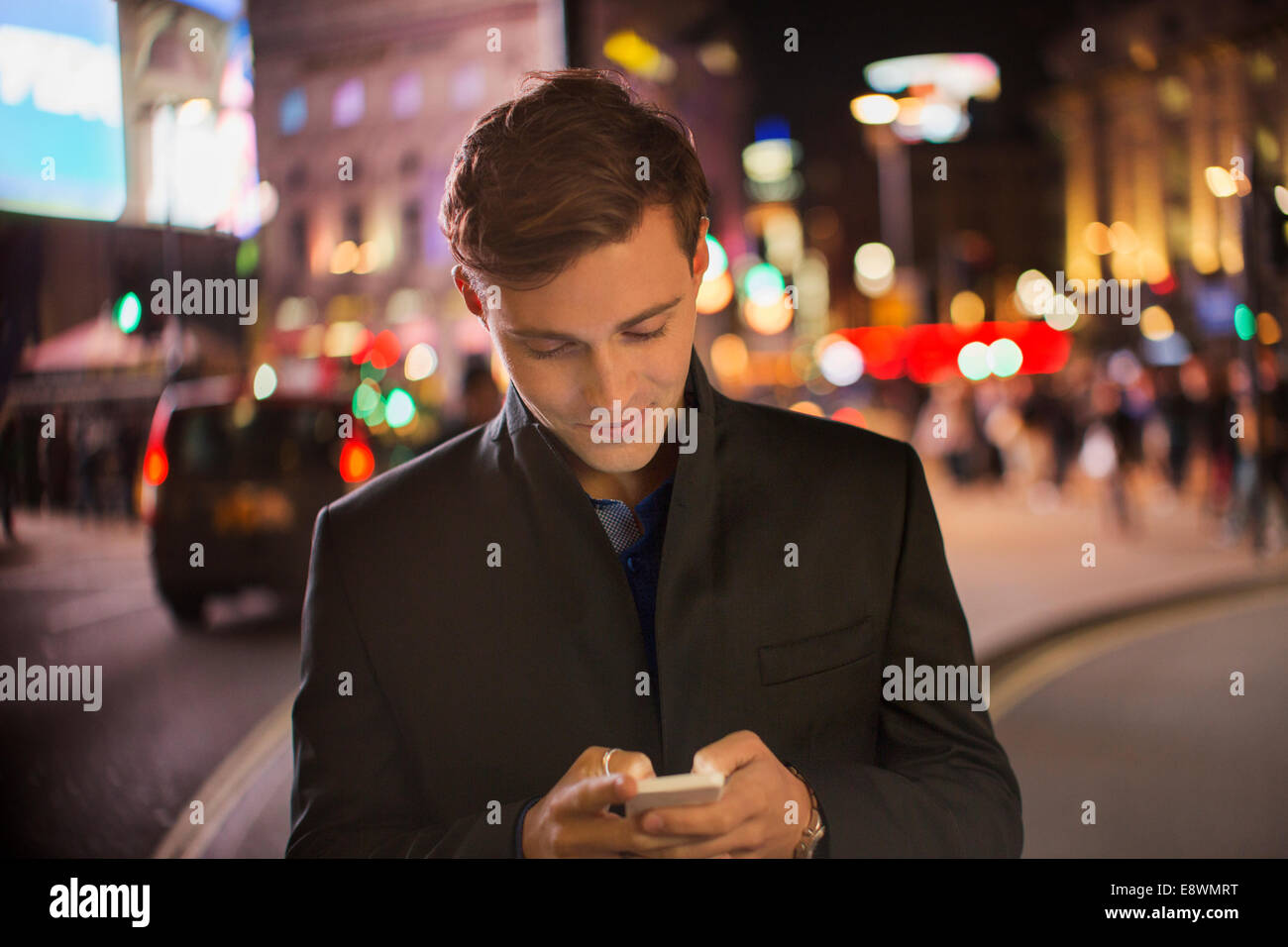 Man using cell phone on city street at night Banque D'Images
