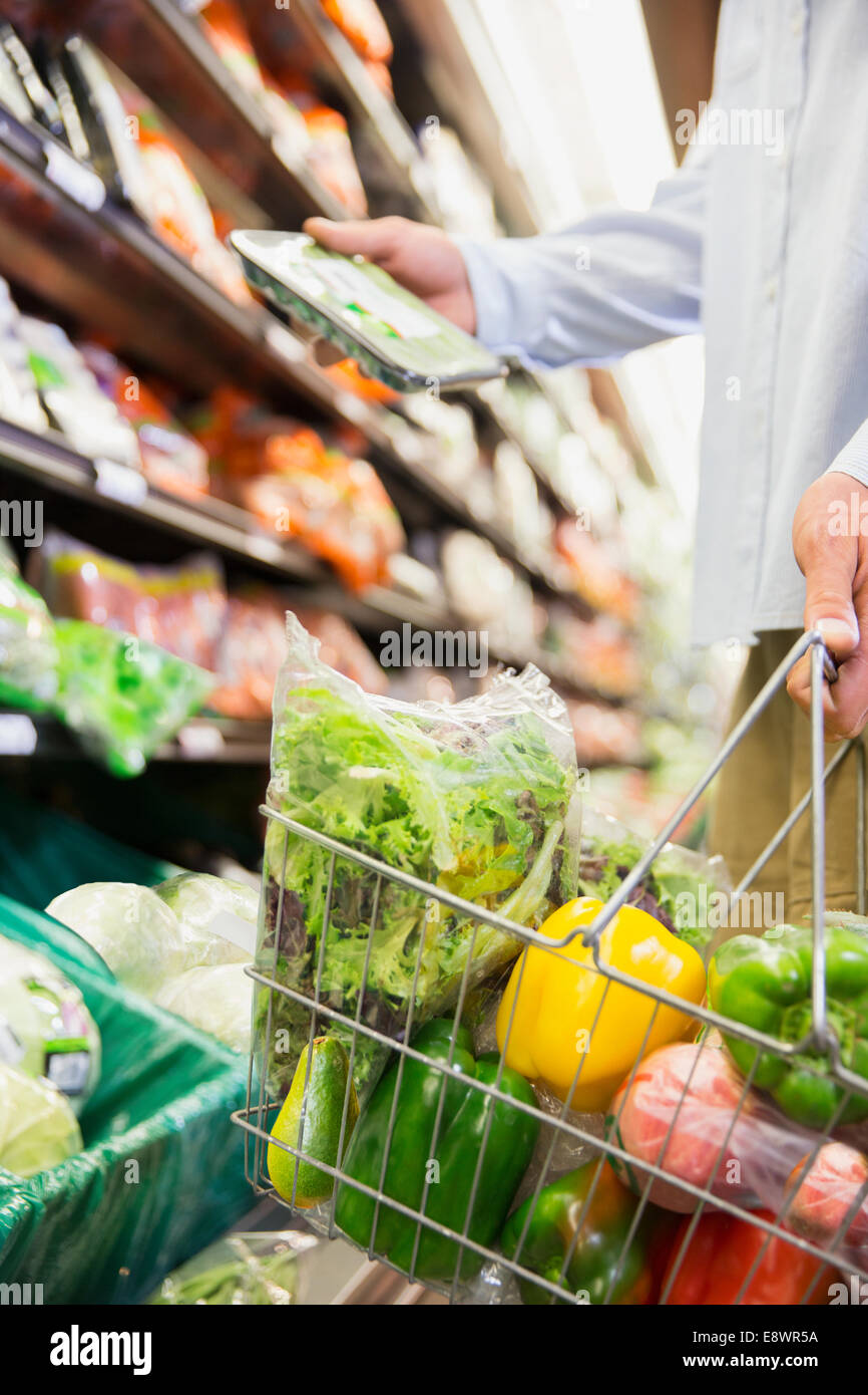 Close up of man holding pleine panier in grocery store Banque D'Images
