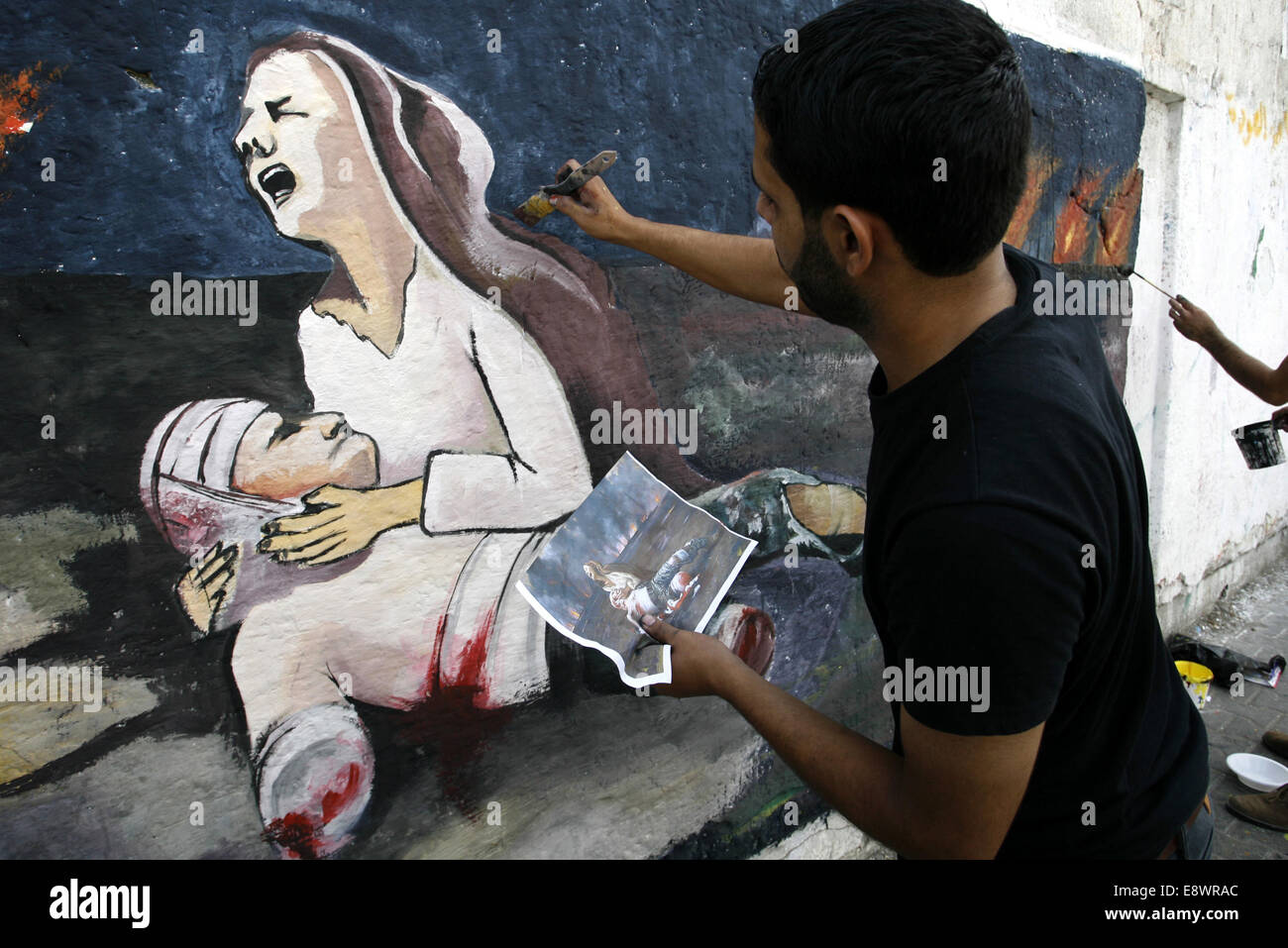 Rafah, bande de Gaza, territoire palestinien. 15 Oct, 2014. Un Palestinien peint une fresque sur un mur dépeint une femme pleurer comme elle tient son mari tués se référant à l'offensive israélienne sept semaines, à Rafah dans le sud de la bande de Gaza, le 5 octobre 2014. Israël a ouvert la frontière pour le premier camion de matériaux de construction pour la reconstruction d'après-guerre à Gaza le mardi et le Secrétaire général de l'ONU, Ban Ki-moon a appelé la destruction dans l'enclave palestinienne ''au-delà description Crédit : Abed Rahim Khatib/APA/Images/fil ZUMA Alamy Live News Banque D'Images