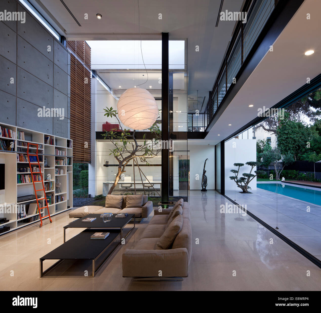 Hauteur double salon avec bibliothèque et une grande poignée de lumière dans Dahan House, Israël, Moyen Orient. Banque D'Images