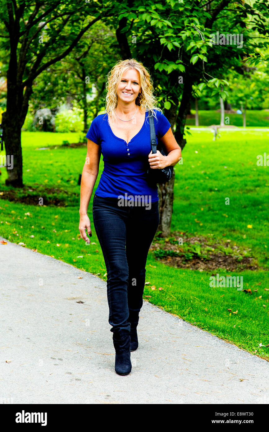 Modèle féminin en vêtements décontractés walking in park Banque D'Images Modèle féminin en vêtements décontractés walking in park Banque D'Images