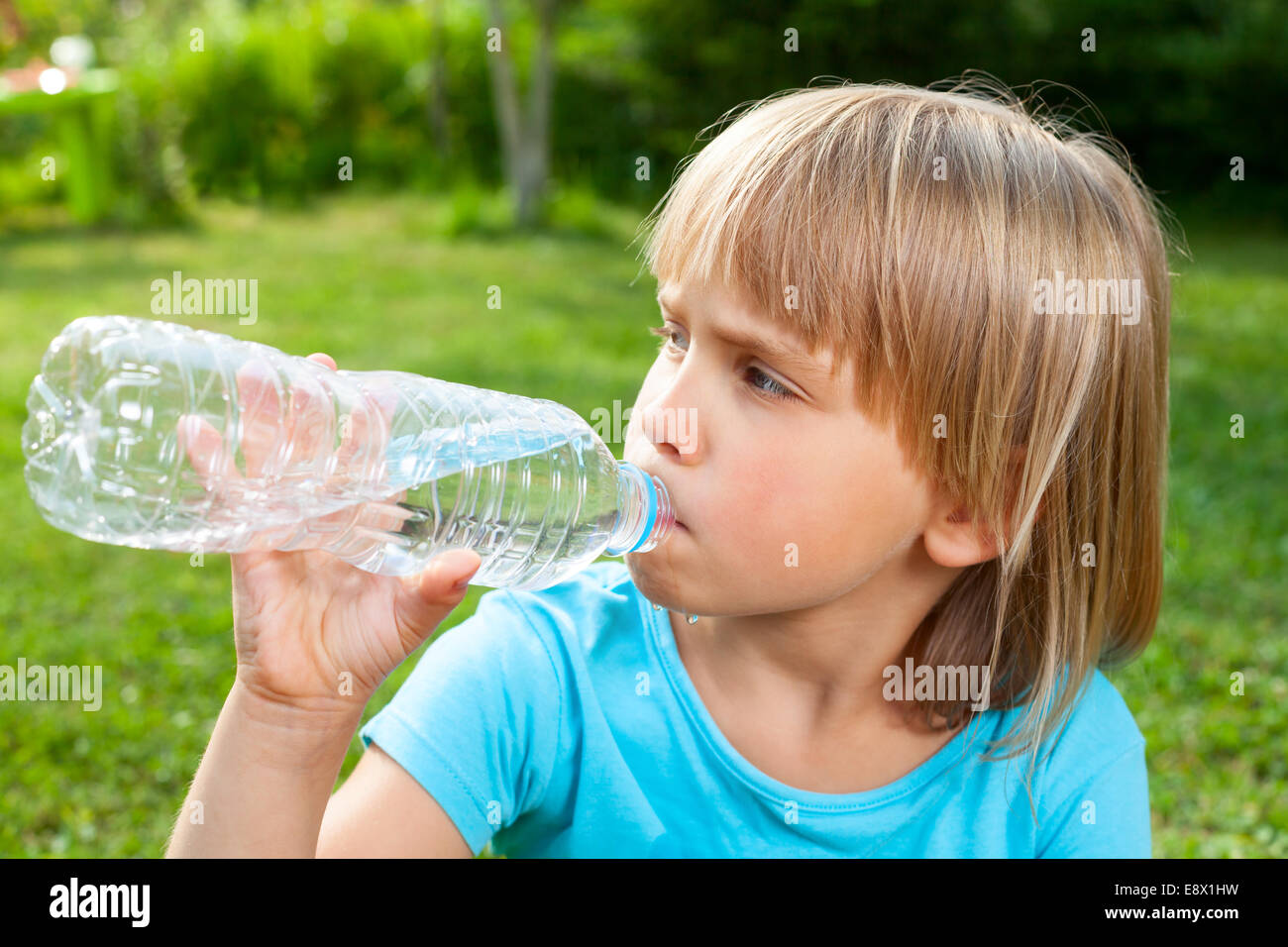 Cute little girl de l'eau potable dans un jardin d'été Banque D'Images