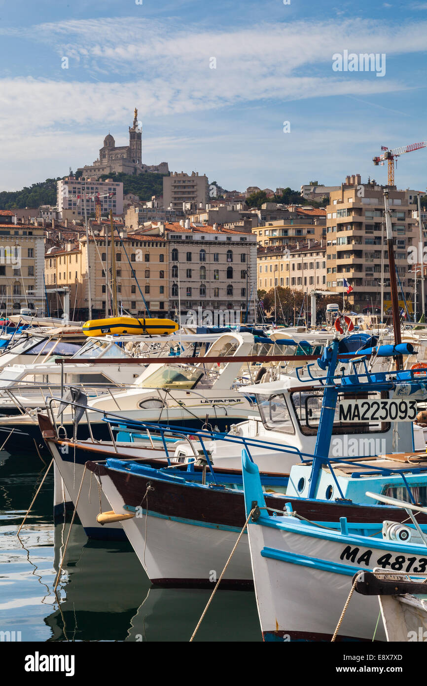 Bateaux de pêche dans le vieux port de Marseille avec la Cathédrale notre dame de la garde sur la colline. Banque D'Images