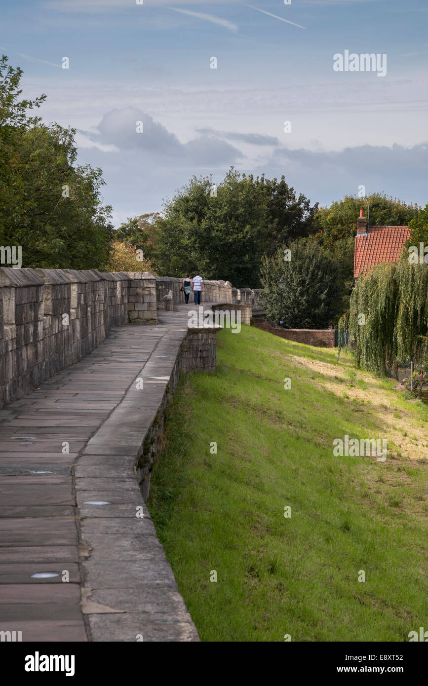 Deux personnes se promènent ensemble le long d'un sentier historique pittoresque sur les murs médiévaux ensoleillés de la ville de York (anciens remparts et parapet) - North Yorkshire, Angleterre, Royaume-Uni. Banque D'Images