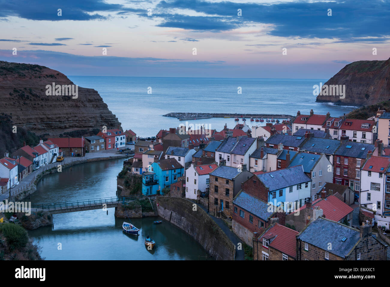 Compte tenu de soirée sunset sky, seaside cottages pittoresques, de hautes falaises et port de vieux village de pêcheurs - Staithes, North Yorkshire Coast, England, UK. Banque D'Images