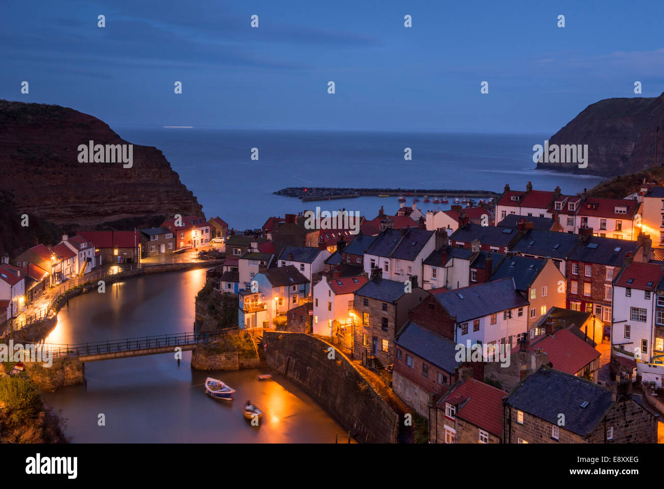 Compte tenu de soirée seaside cottages pittoresques (allumés) de hautes falaises et port de vieux village de pêcheurs - Staithes, North Yorkshire Coast, England, UK. Banque D'Images