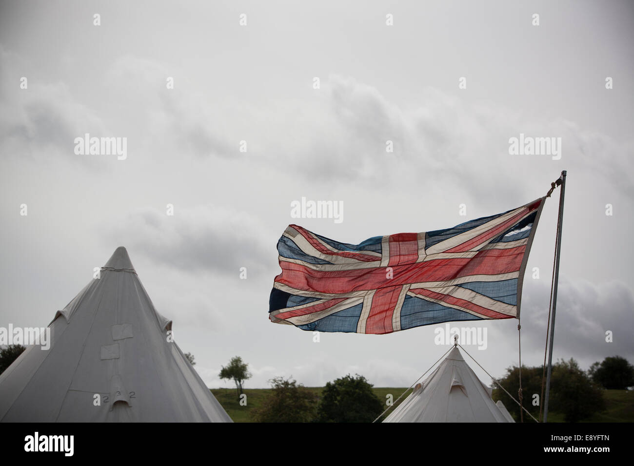 Un vintage ww1 période Union Jack britannique, le drapeau qui flotte en berne complet, avec deux tentes de camping de l'armée de toile à l'arrière-plan. Banque D'Images