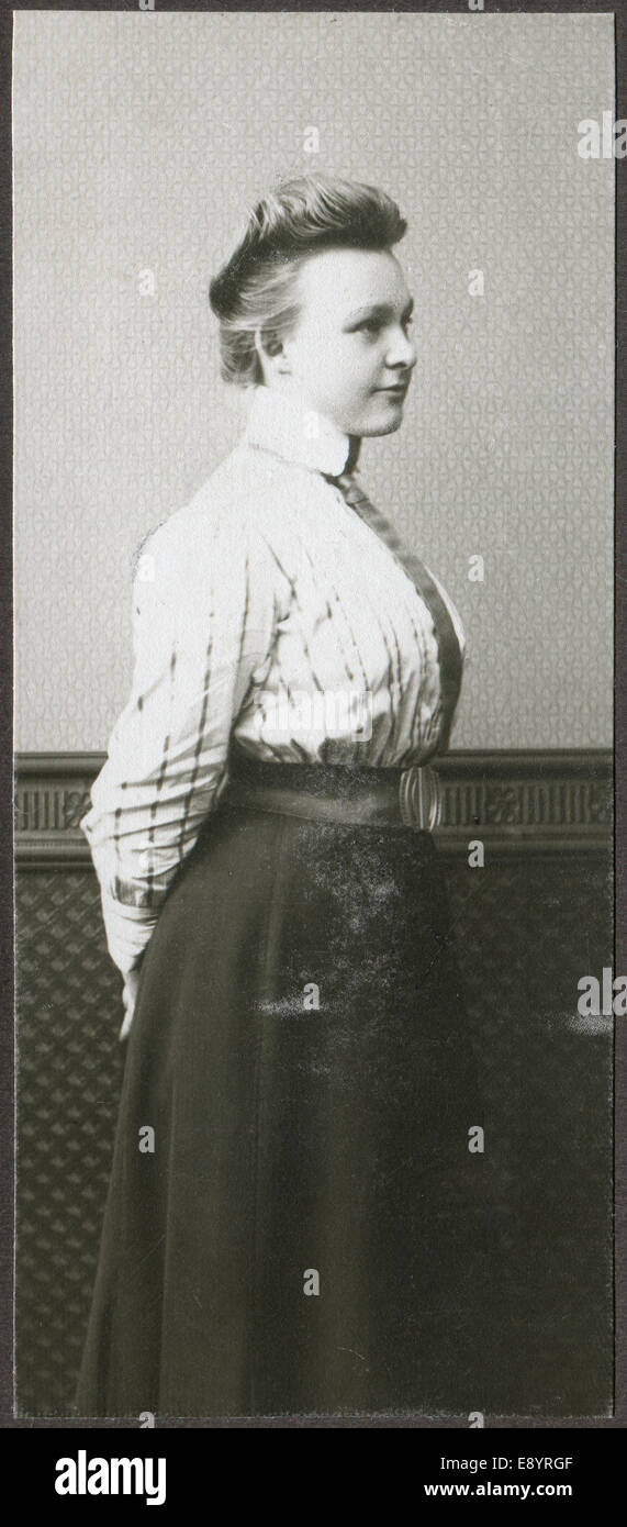 Un vintage portrait of young woman, demi-permanent s'est tourné vers le mur, vêtu d'une blouse et jupe longue Banque D'Images