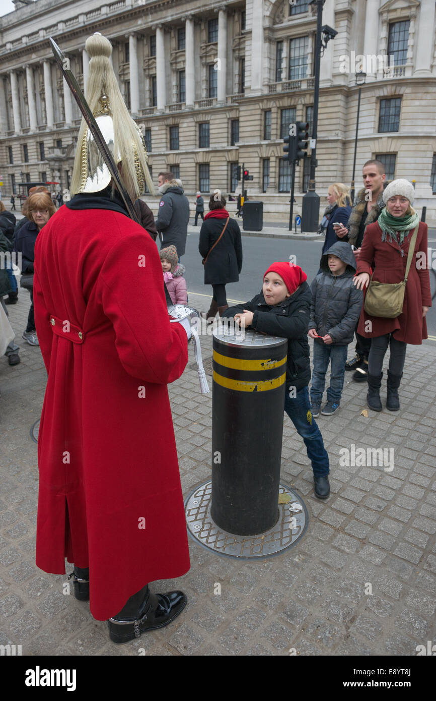 Enfant pulling faces à un membre de la Household Cavalry Regiment, gardiens de la vie, qui monte la garde à l'extérieur de Horse Guards Parade, Londres, Angleterre Banque D'Images