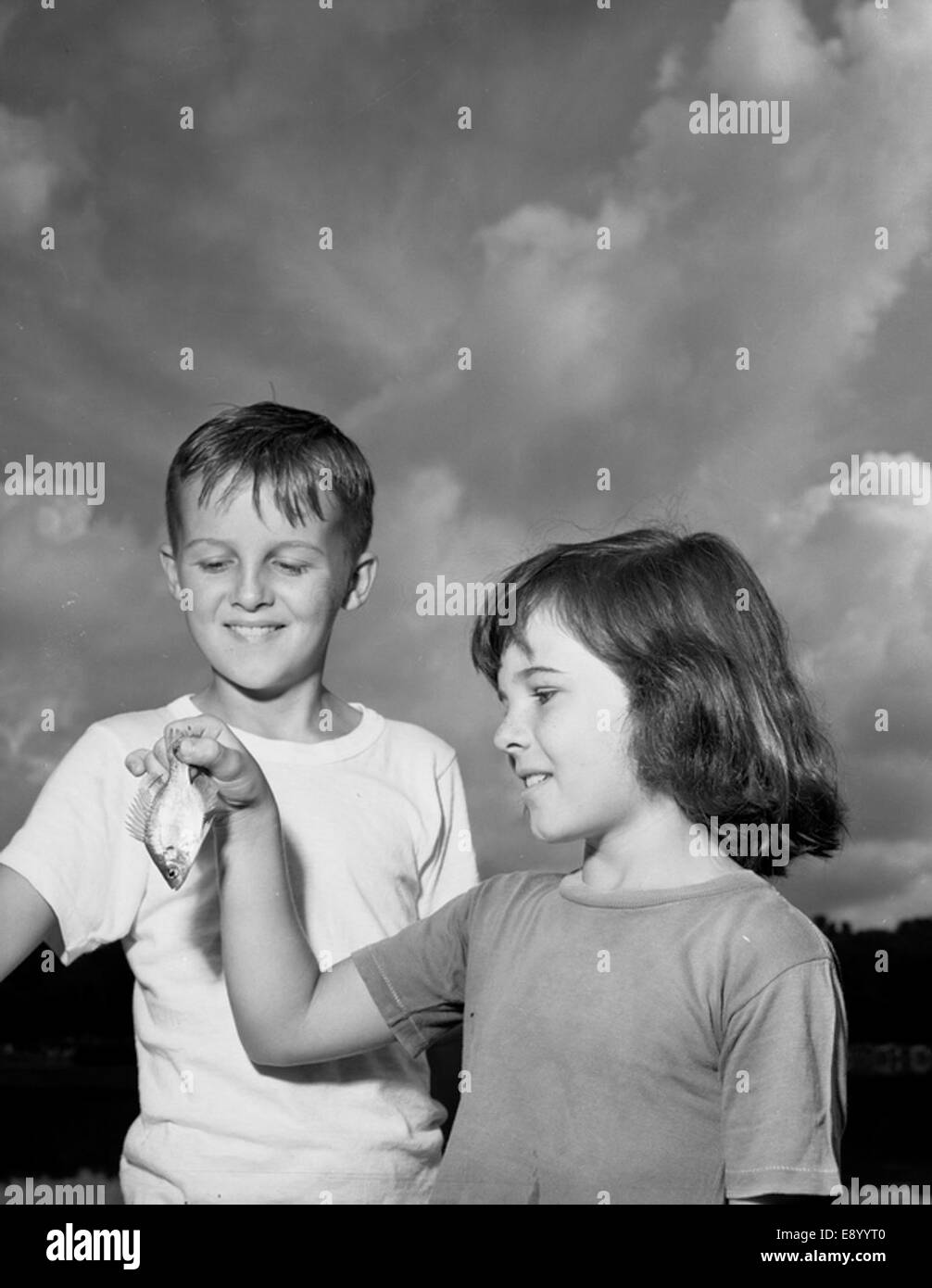 Une photographie de Patsey Moore montrant fièrement à son frère le poisson qu'elle a attrapé. Cela capture un moment de lien familial et de loisirs en plein air. Banque D'Images