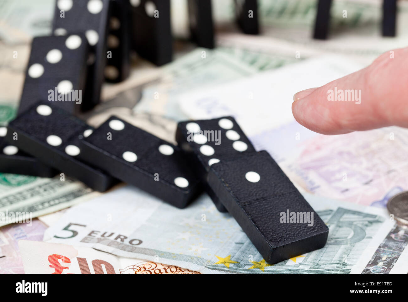 Doigt sur dominos sur les billets de banque Banque D'Images