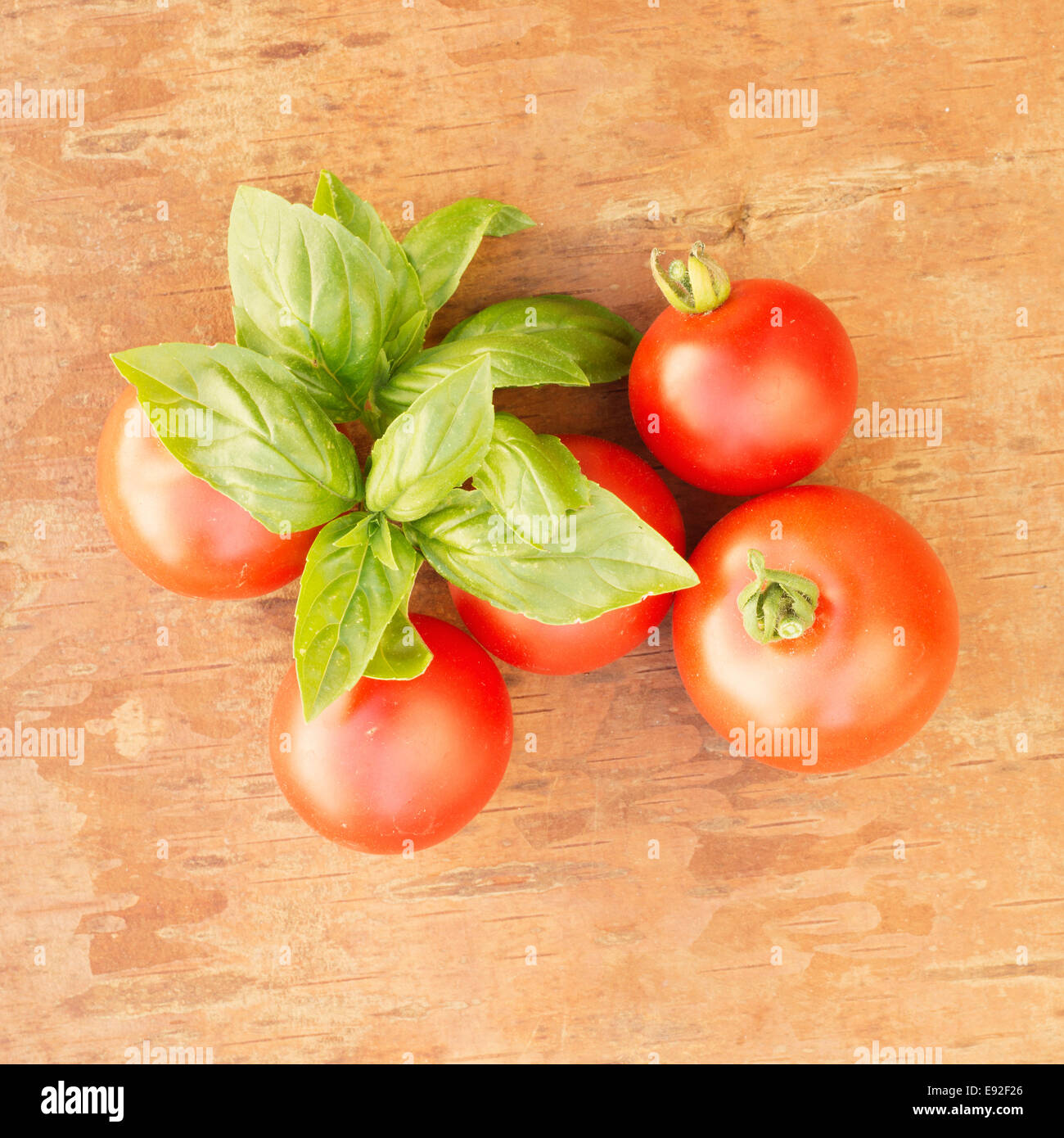 La vie encore de tomates fraîches et de feuilles de basilic sur la surface en bois Banque D'Images
