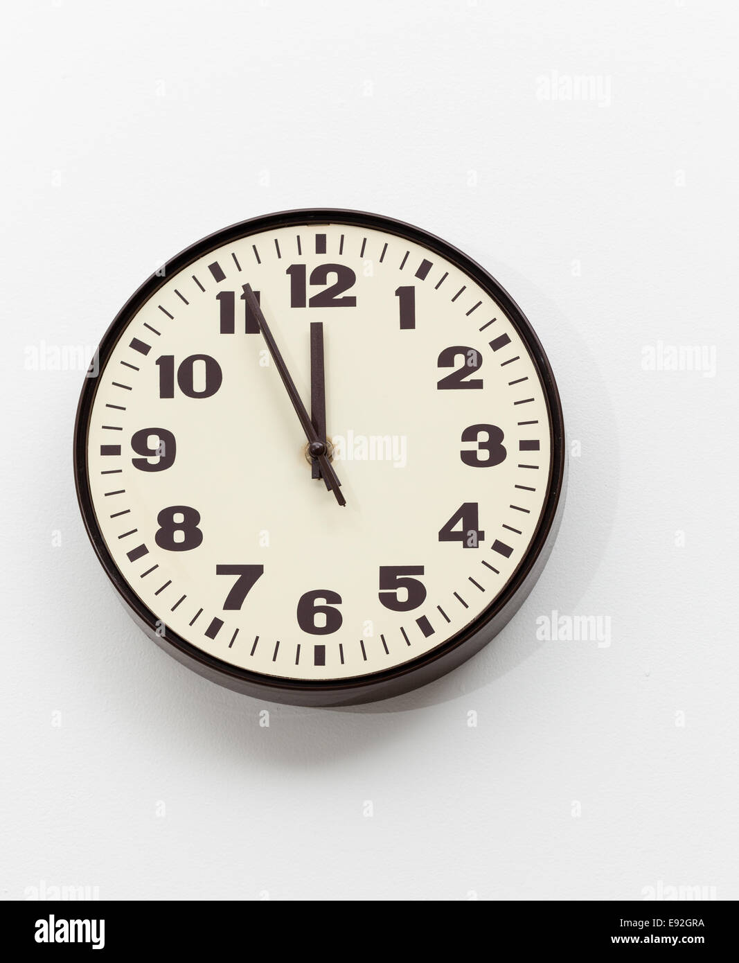 Horloge marron blanc sur mur de bureau vers midi Banque D'Images