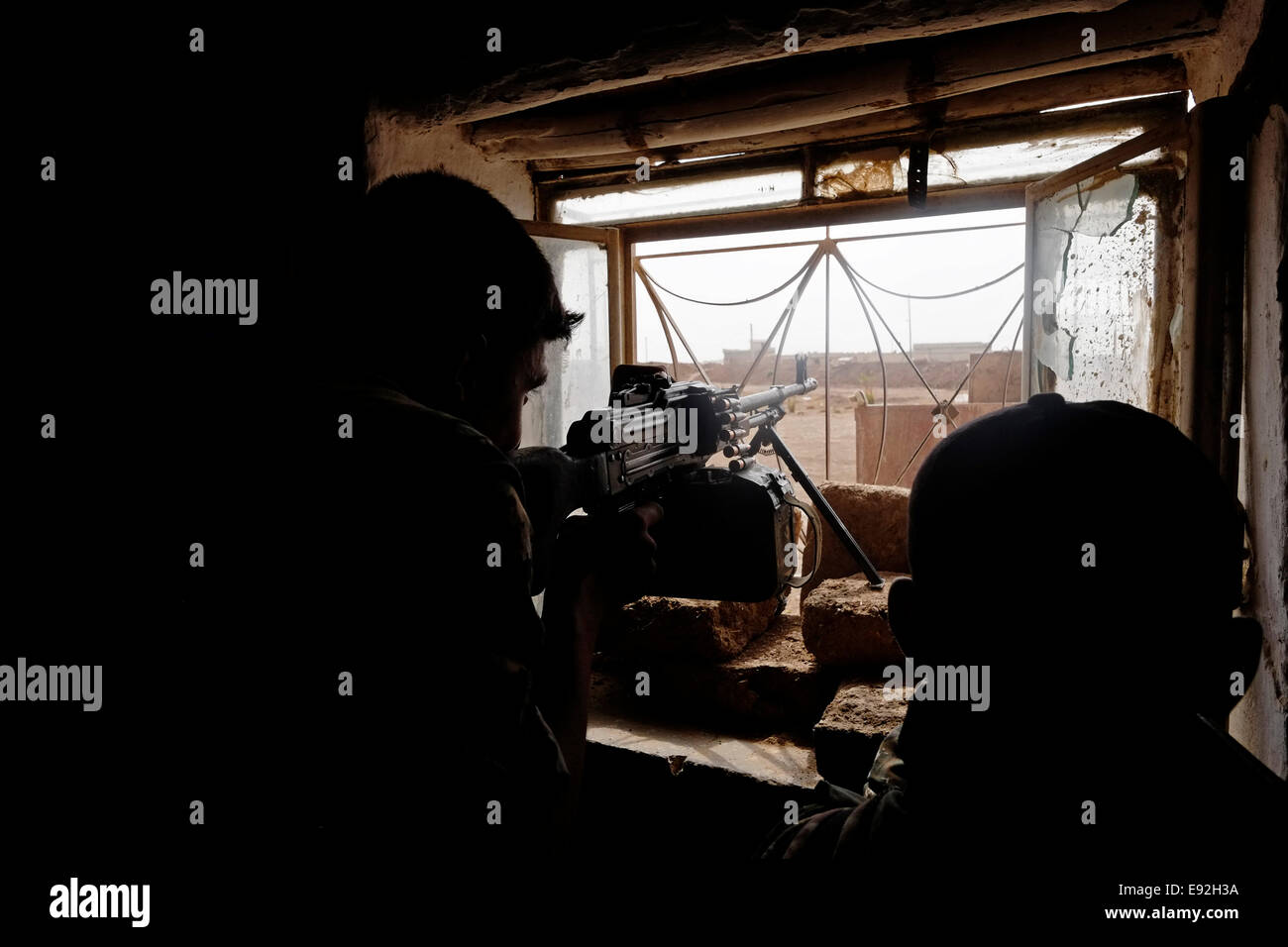 Un combattant de l'unité de protection du peuple kurde GPJ tir avec PK 7,62 mm machine gun à ISIS ou ISIL cibles dans Al Hasakah ou Hassakeh district dans Rojava de facto la région autonome kurde originaires et composée de trois cantons autonomes dans le nord de la Syrie Banque D'Images