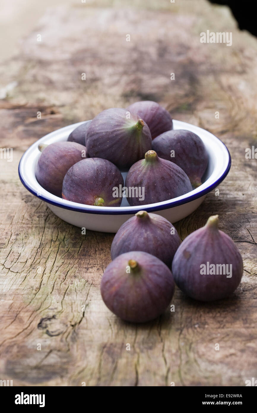 Ficus carica. Figues dans un plat en émail sur une planche de bois. Banque D'Images