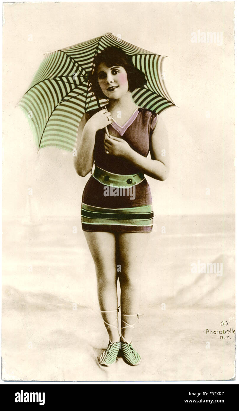 Femme en maillot rayé marron et vert, parasol à rayures Service Standing on Beach, Hand-Colored, carte postale, vers 1900 Banque D'Images