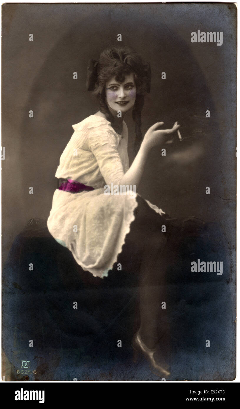 Femme assise en robe blanche et ceinture rouge Cigarette, Hand-Colored Postcard, Allemagne, vers 1920 Banque D'Images