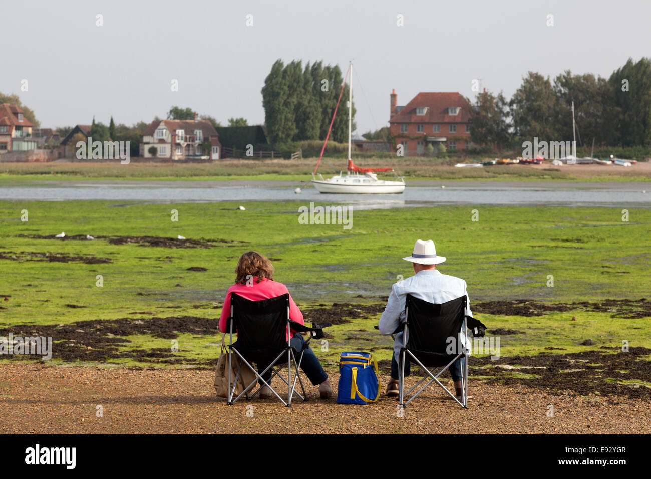 Couple assis à côté du port à marée basse, Bosham, West Sussex Banque D'Images