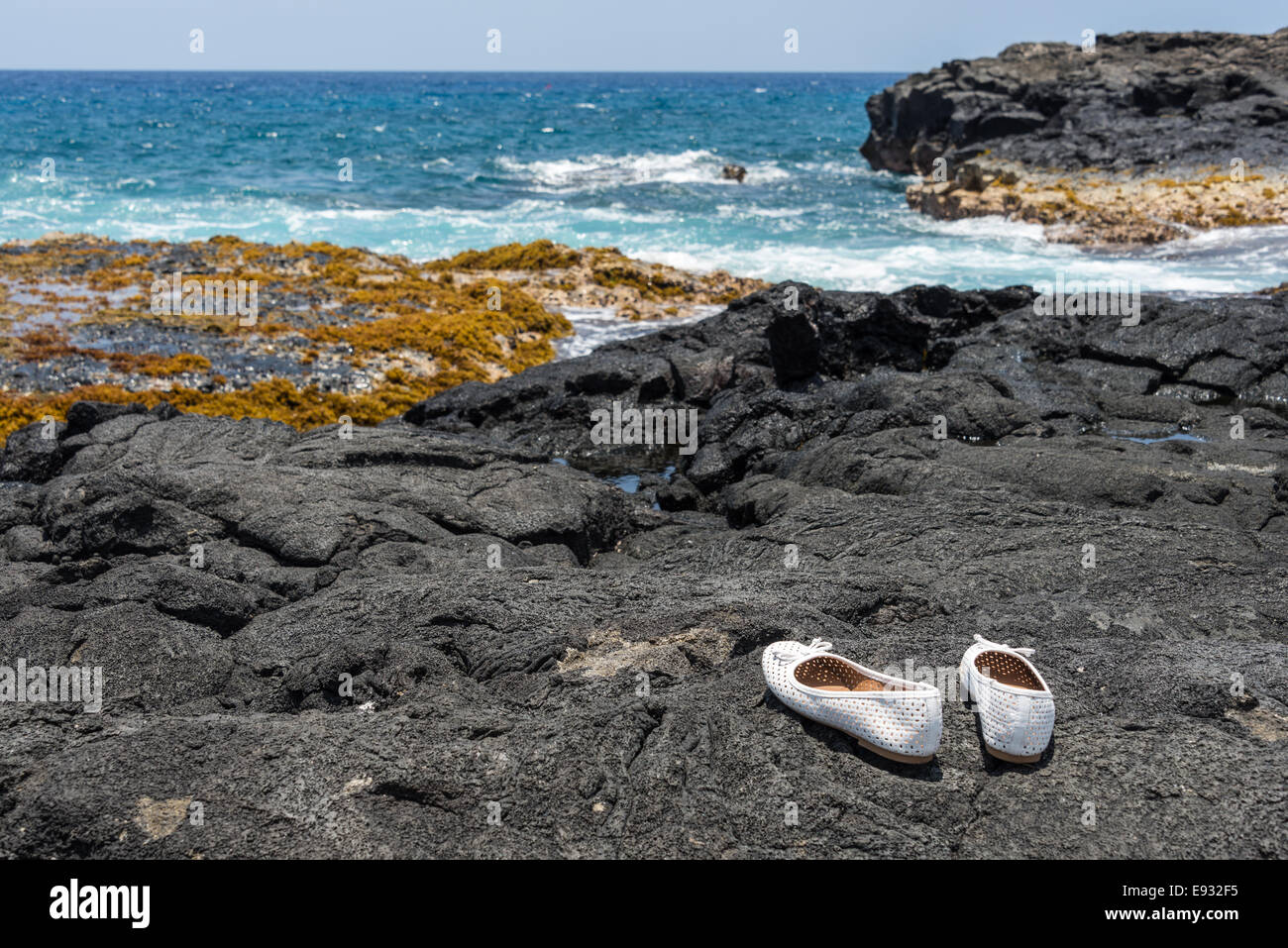 Chaussures blanches à Hawaii gauche sur la pierre de lave noire Banque D'Images