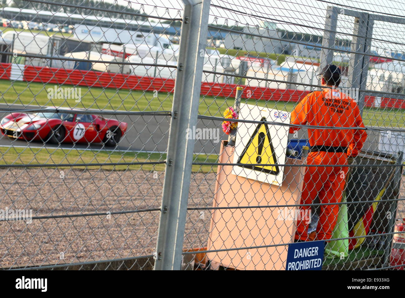 Voitures de course classique passé un commissaire de pistes au cours d'une réunion pour les voitures historiques au Silverstone Classic 2014. Banque D'Images