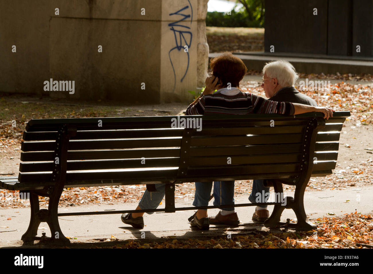 Couple assis sur le banc de l'écriture graffiti touristes soleil sur téléphone portable Banque D'Images