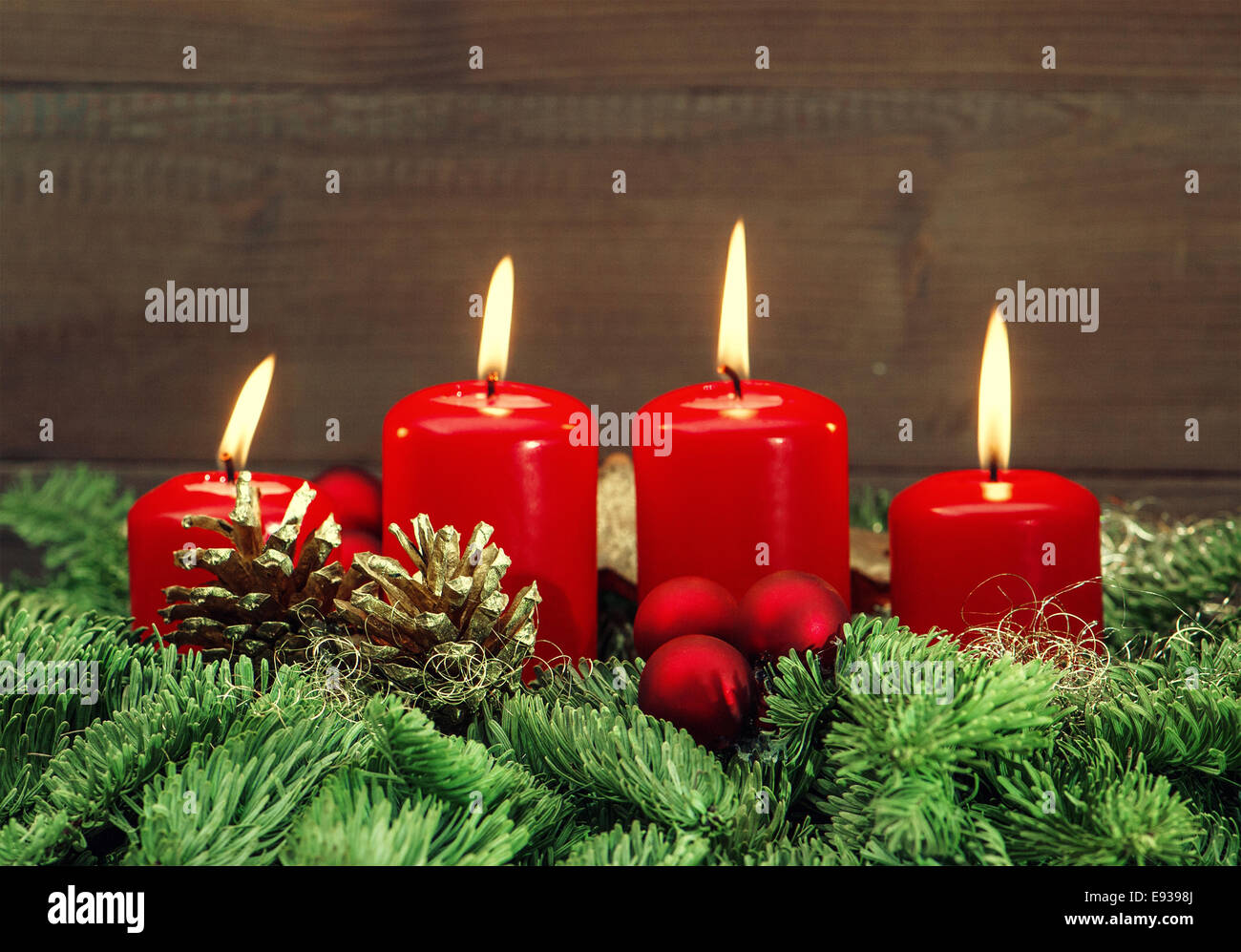 La décoration de l'avent festive avec quatre boules rouge brûler des bougies, et des branches d'arbre de Noël en arrière-plan des vacances. Banque D'Images