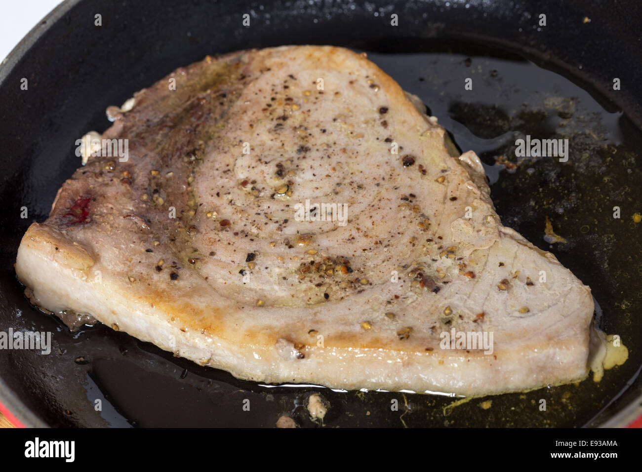 Un steak d'espadon saupoudrée de poivre concassé dans une poêle à frire Banque D'Images