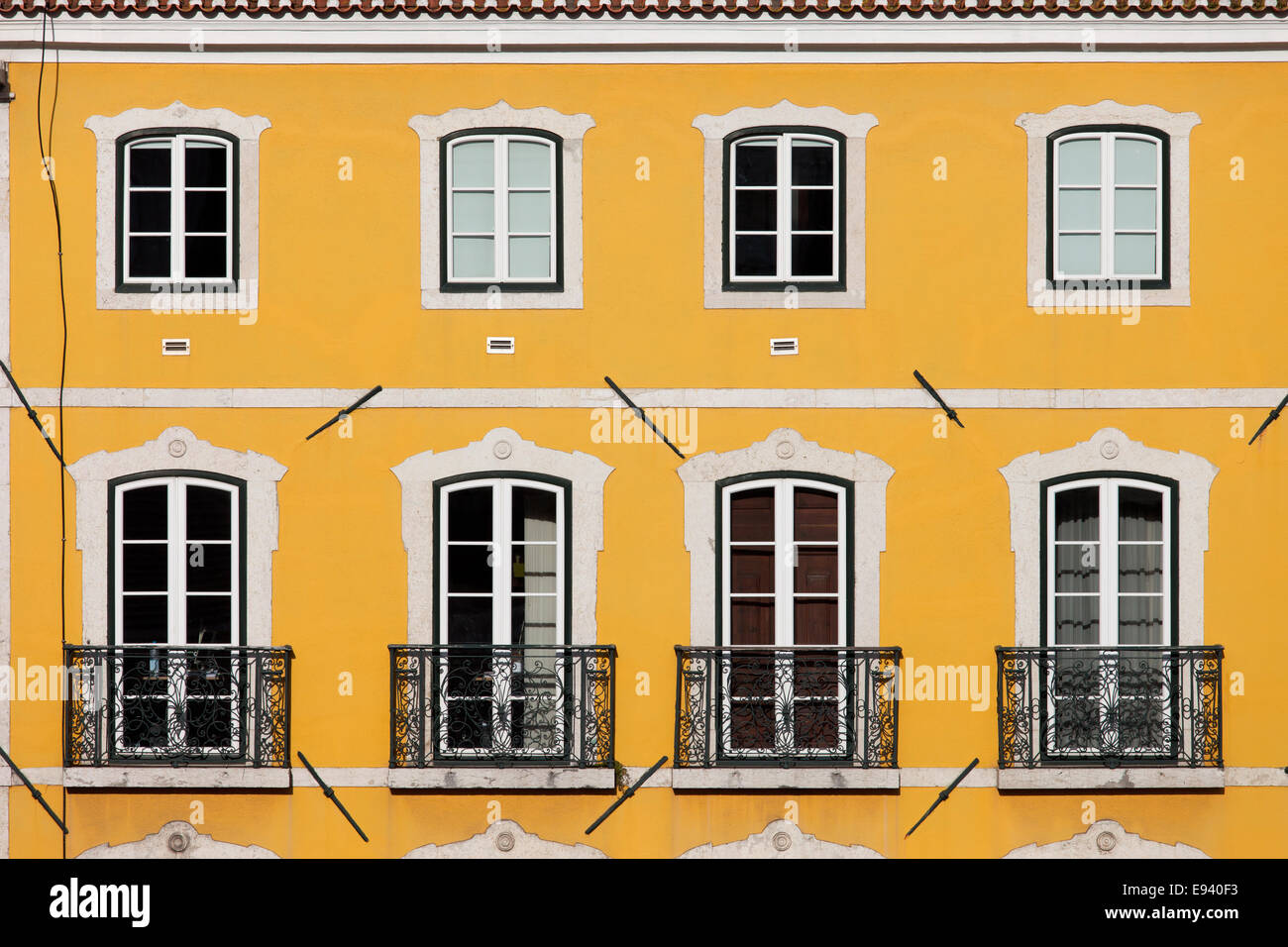 Maison traditionnelle avec façade jaune et de grandes fenêtres avec balconets à Lisbonne, Portugal. Banque D'Images