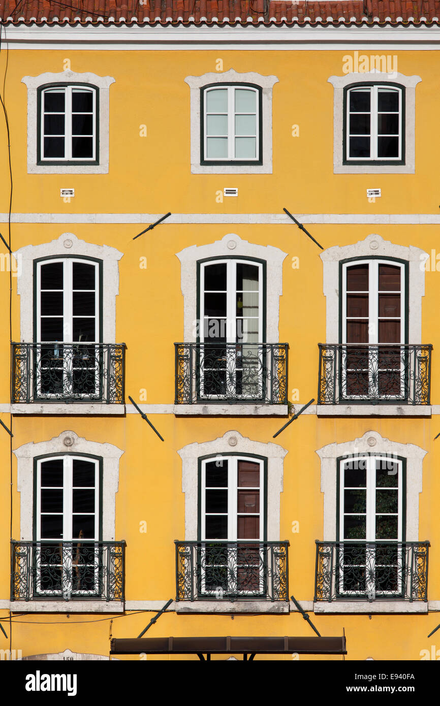 Bâtiment traditionnel avec une façade jaune et de grandes fenêtres avec balconets à Lisbonne, Portugal. Banque D'Images