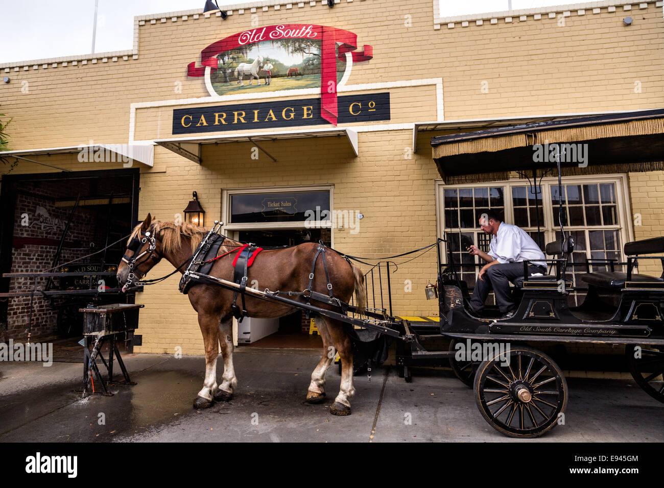 Visite d'un conducteur de chariot attend avec son cheval à l'extérieur de l'ancienne grange du chariot du Sud dans la ville historique de Charleston, SC. Banque D'Images