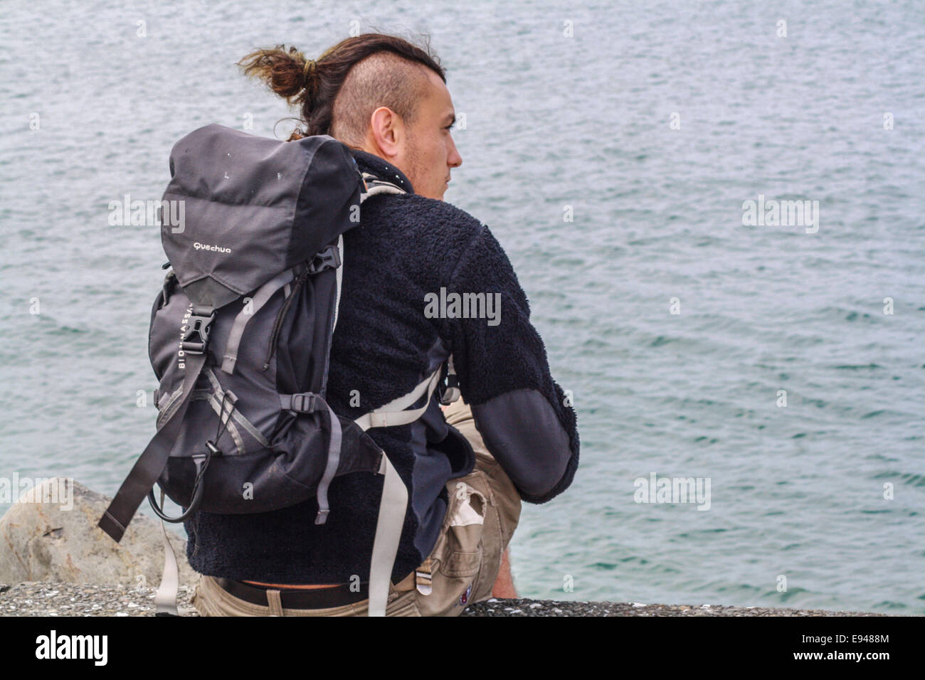 Les jeunes hommes adultes assis sur les roches du littoral Banque D'Images