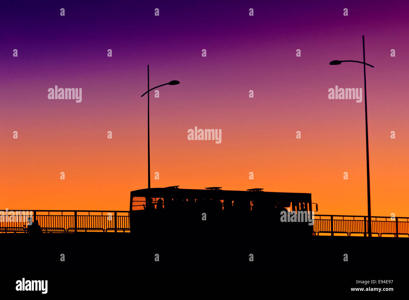 Silhouette city bus traversant le pont au coucher du soleil, les transports publics. Banque D'Images