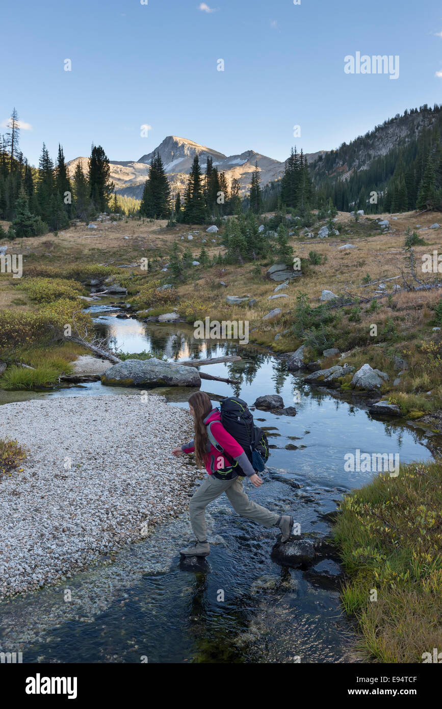 Backpacker traversant un ruisseau dans les montagnes de l'Oregon Wallowa. Cap de l'aigle pic est dans l'arrière-plan. Banque D'Images