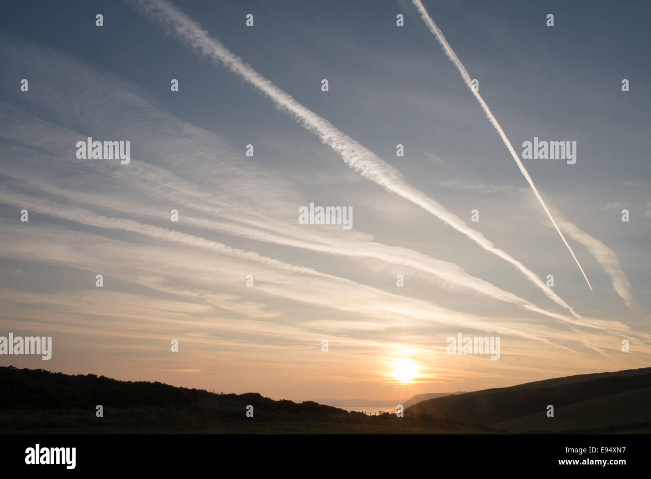 Des traînées de vapeur chimique,plans,sentiers, sunrise Mwnt,West Wales Banque D'Images