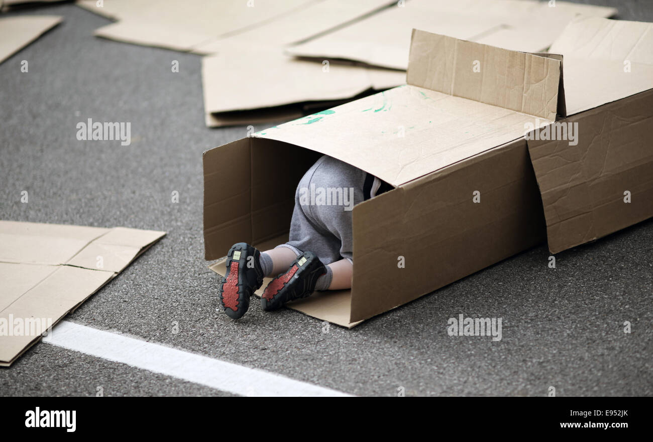 Un enfant se faufiler dans une boîte en carton. Banque D'Images