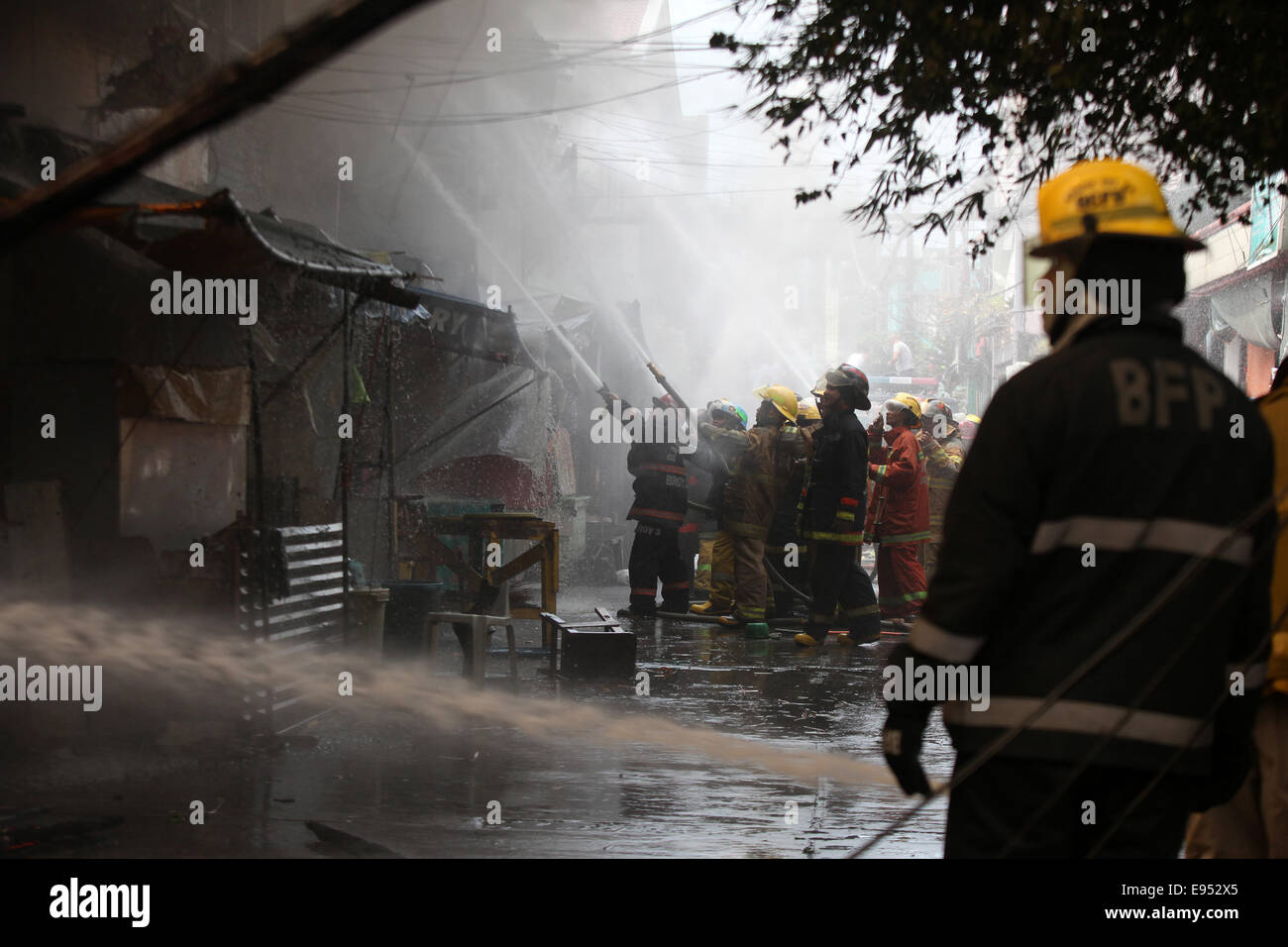 Manille. 20 Oct, 2014. Les pompiers tentent d'éteindre un incendie qui a frappé une zone résidentielle à Manille aux Philippines le 20 octobre 2014. Le feu à gauche, 150 familles sans-abri. Credit : Rouelle Umali/Xinhua/Alamy Live News Banque D'Images